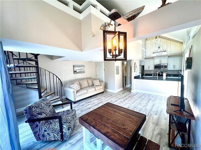 2695 N Seabreeze Pt, Crystal River, FL 34429 - living room featuring a high ceiling, light wood-style floors, a chandelier, stairway, and baseboards