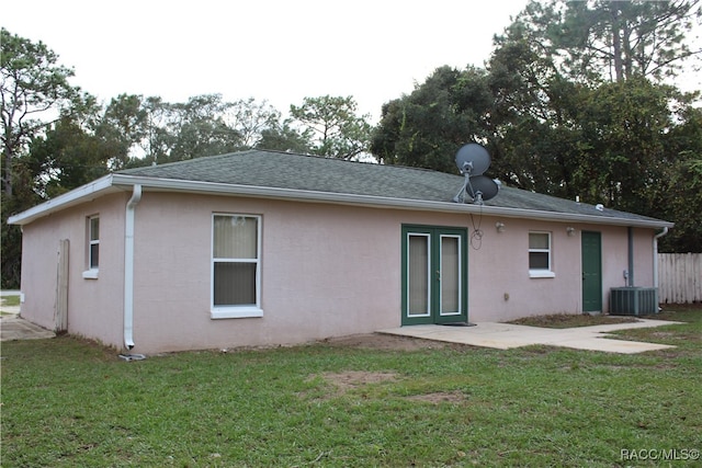 rear view of property featuring central air condition unit and a lawn