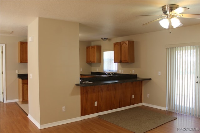 kitchen featuring kitchen peninsula, a textured ceiling, light wood-type flooring, and ceiling fan