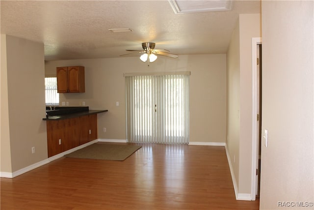 unfurnished living room with hardwood / wood-style flooring, ceiling fan, and a textured ceiling