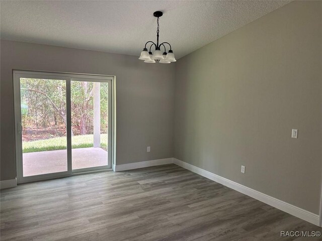 3289 W Camilo Dr, Dunnellon, FL 34433 - empty room featuring wood finished floors, a chandelier, and a textured ceiling