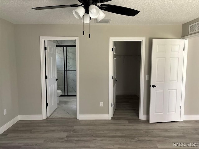 3289 W Camilo Dr, Dunnellon, FL 34433 - unfurnished bedroom featuring a spacious closet, a textured ceiling, a closet, connected bathroom, and wood finished floors