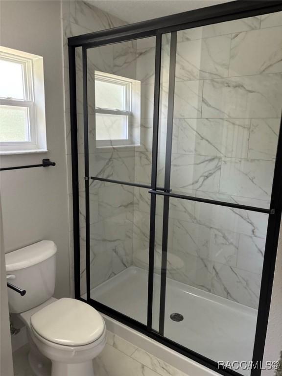 3289 W Camilo Dr, Dunnellon, FL 34433 - bathroom with a shower stall, marble look tile flooring, and healthy amount of natural light