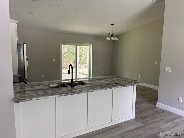 3289 W Camilo Dr, Dunnellon, FL 34433 - kitchen with white cabinets, freestanding refrigerator, wood finished floors, a chandelier, and pendant lighting