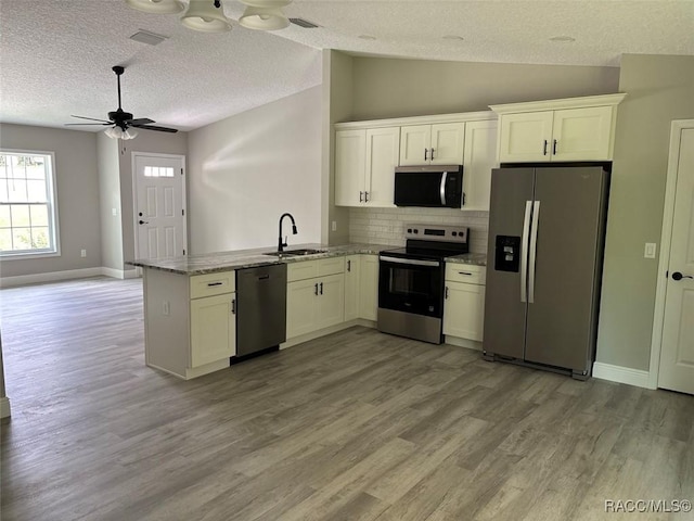3289 W Camilo Dr, Dunnellon, FL 34433 - kitchen with stainless steel appliances, a peninsula, tasteful backsplash, light wood-style flooring, and a textured ceiling