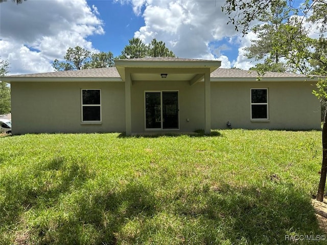 3289 W Camilo Dr, Dunnellon, FL 34433 - rear view of property with stucco siding and a lawn