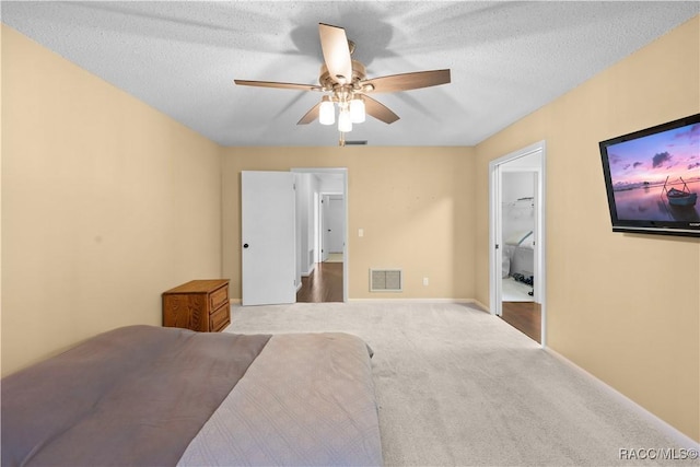 carpeted bedroom featuring ensuite bathroom, a textured ceiling, and ceiling fan