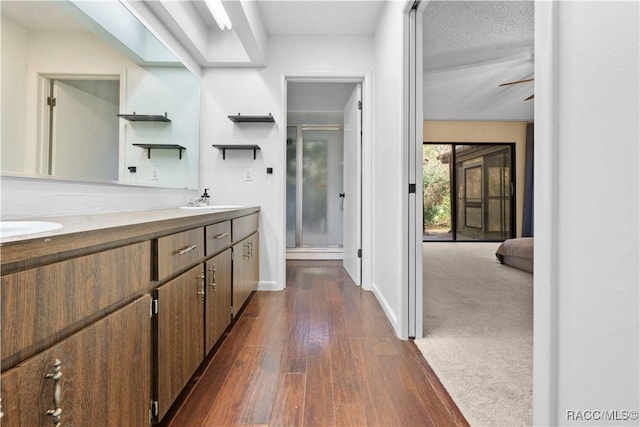 bathroom with vanity, wood-type flooring, a textured ceiling, and walk in shower