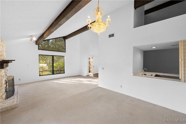 unfurnished living room with beam ceiling, high vaulted ceiling, carpet flooring, a notable chandelier, and a stone fireplace