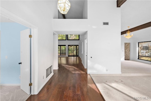 hall featuring beam ceiling, a towering ceiling, a notable chandelier, and dark hardwood / wood-style flooring