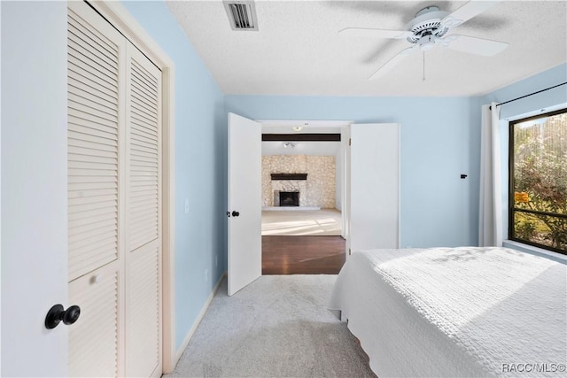 bedroom with ceiling fan, light colored carpet, a closet, and a textured ceiling