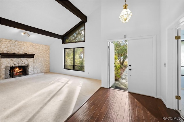 entrance foyer featuring beam ceiling, a stone fireplace, dark hardwood / wood-style floors, and high vaulted ceiling