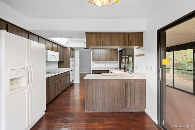 kitchen featuring sink, white appliances, dark hardwood / wood-style floors, a textured ceiling, and kitchen peninsula