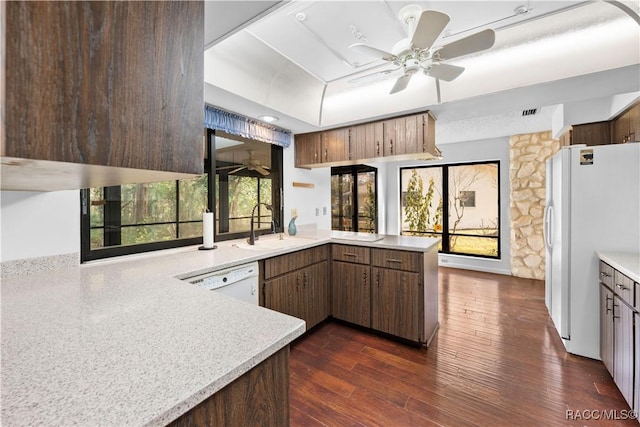 kitchen with white appliances, plenty of natural light, kitchen peninsula, and dark wood-type flooring