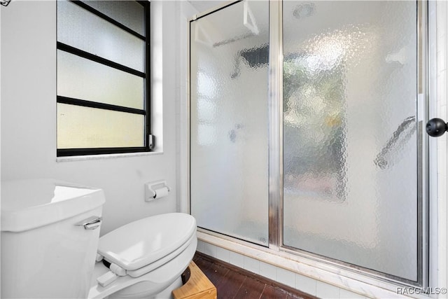 bathroom featuring hardwood / wood-style flooring, toilet, and a shower with shower door