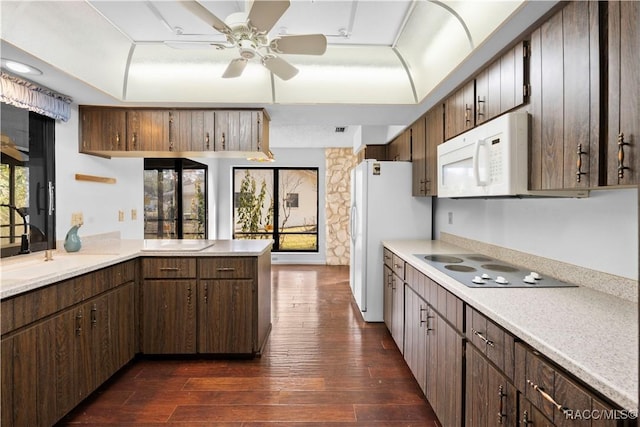 kitchen with sink, white appliances, ceiling fan, dark hardwood / wood-style flooring, and kitchen peninsula