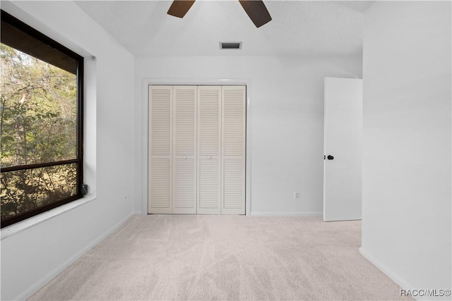 unfurnished bedroom featuring light carpet, ceiling fan, and a closet