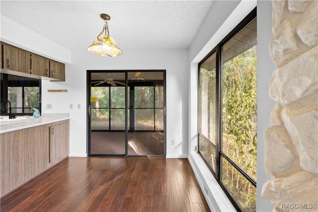 kitchen featuring sink, decorative light fixtures, a textured ceiling, dark hardwood / wood-style flooring, and ceiling fan