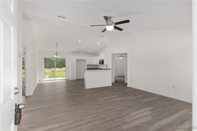 unfurnished living room with wood-type flooring, ceiling fan with notable chandelier, and high vaulted ceiling