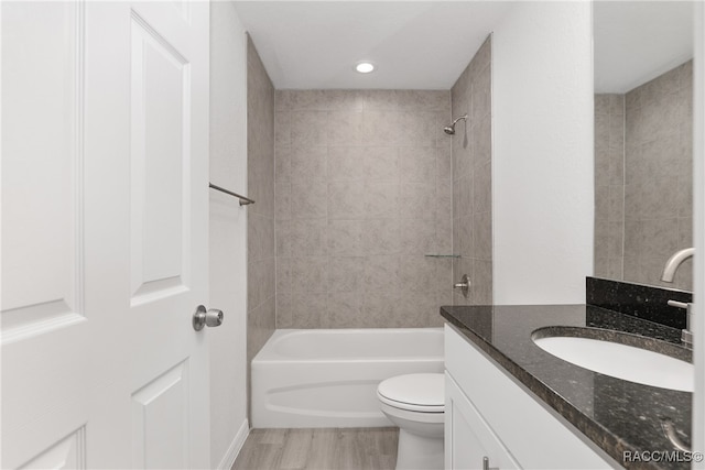 full bathroom featuring hardwood / wood-style floors, vanity, toilet, and tiled shower / bath