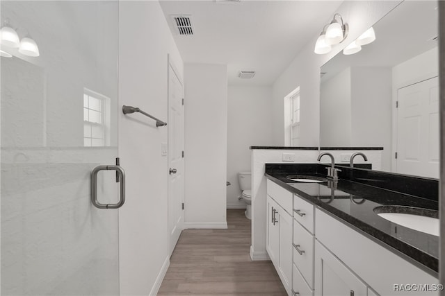 bathroom with a shower with door, vanity, wood-type flooring, and toilet