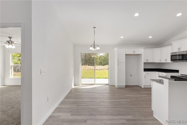 kitchen featuring white cabinetry, a wealth of natural light, pendant lighting, and vaulted ceiling