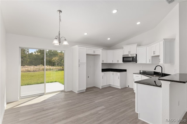 kitchen featuring white cabinetry, hanging light fixtures, lofted ceiling, and sink