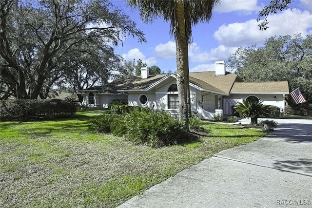 view of front of house with a front lawn, an attached garage, driveway, and stucco siding