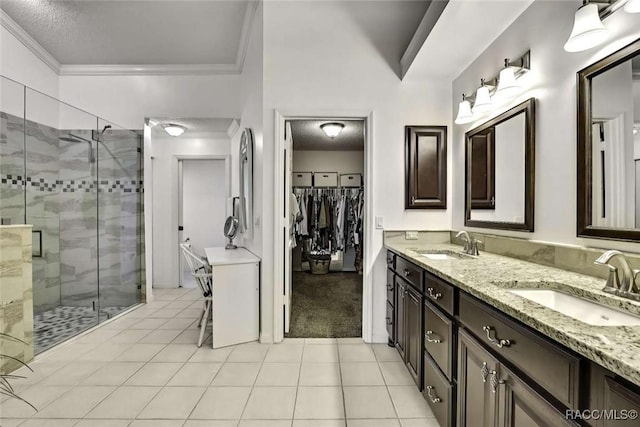 full bath with double vanity, a shower stall, crown molding, and a sink