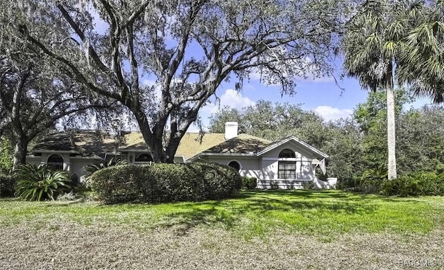 exterior space featuring stucco siding, a lawn, and a chimney