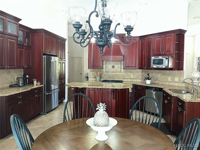 kitchen featuring a sink, a kitchen island, stainless steel appliances, an inviting chandelier, and dark brown cabinets