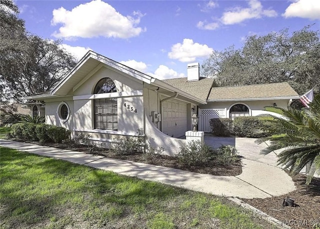 view of front of house featuring stucco siding, a chimney, concrete driveway, and an attached garage