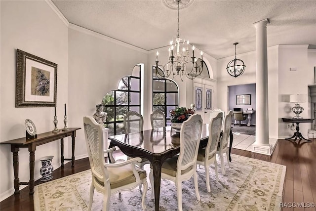 dining area featuring an inviting chandelier, wood-type flooring, ornate columns, and a textured ceiling