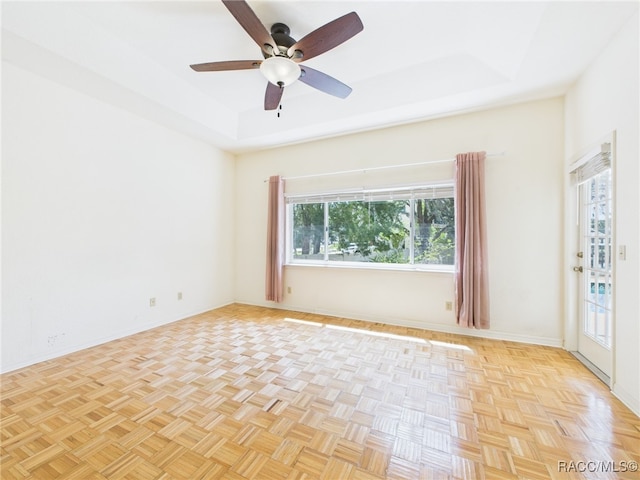 empty room featuring a ceiling fan, baseboards, and a raised ceiling