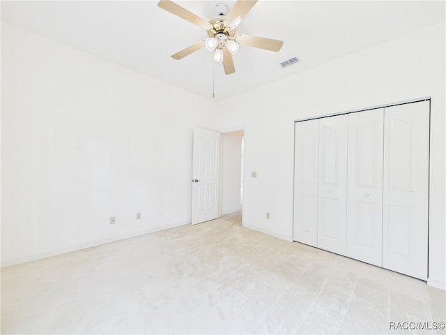 unfurnished bedroom with a ceiling fan, light colored carpet, visible vents, baseboards, and a closet