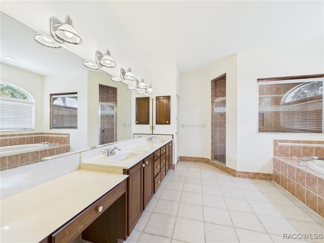 bathroom featuring tile patterned flooring, a sink, a garden tub, and a shower stall