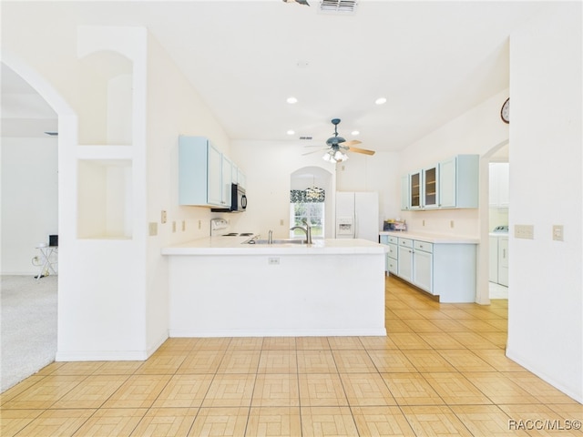 kitchen with ceiling fan, white refrigerator with ice dispenser, light countertops, a peninsula, and glass insert cabinets