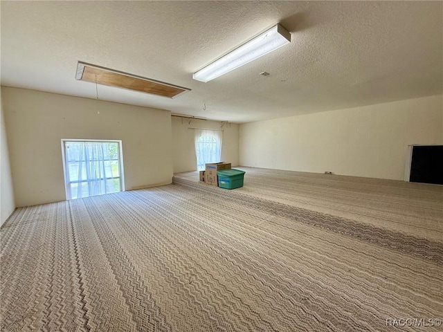 spare room featuring a textured ceiling, carpet, and attic access