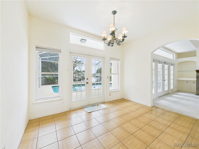 doorway to outside with french doors, arched walkways, baseboards, and an inviting chandelier