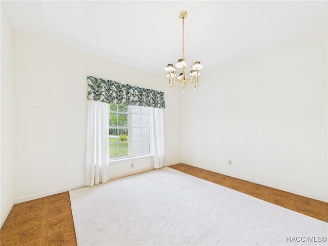 empty room with baseboards and a notable chandelier