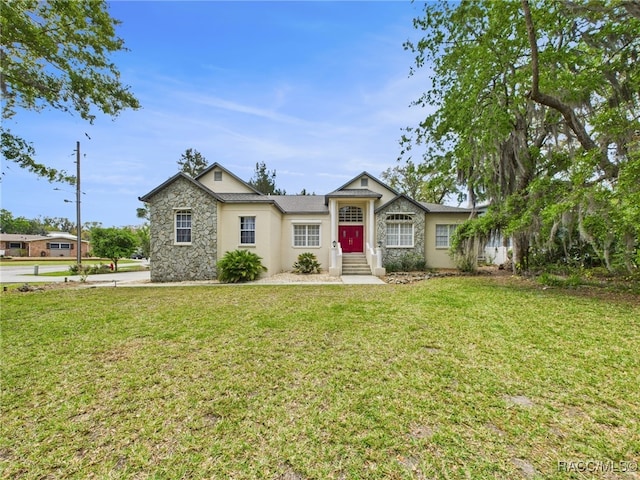 ranch-style home featuring entry steps, stucco siding, a front lawn, and stone siding