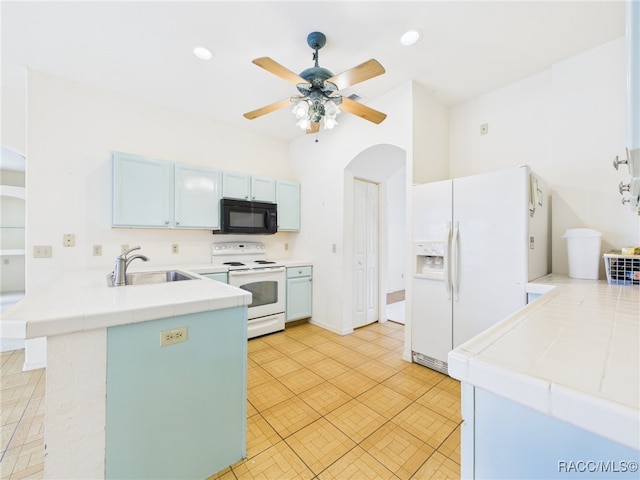 kitchen featuring arched walkways, a sink, a peninsula, tile counters, and white appliances