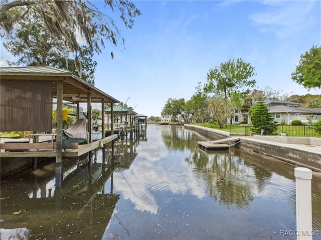 view of dock with boat lift, fence, and a water view