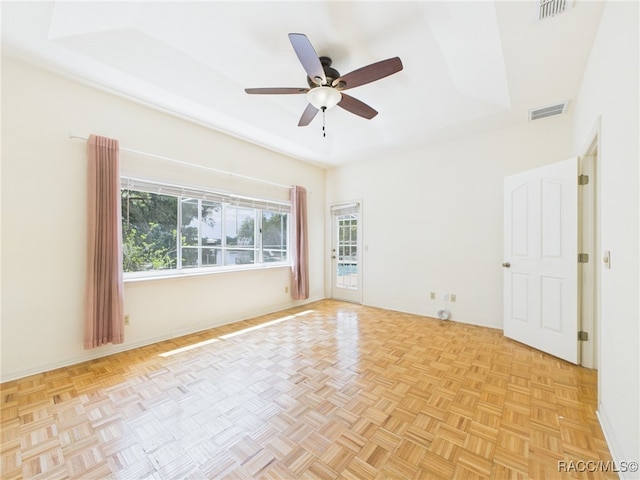 spare room with a ceiling fan, a tray ceiling, and visible vents
