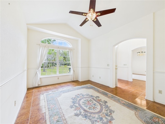 spare room featuring ceiling fan with notable chandelier, arched walkways, and vaulted ceiling