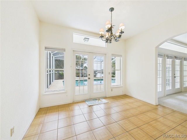 doorway featuring tile patterned flooring, baseboards, french doors, arched walkways, and a notable chandelier