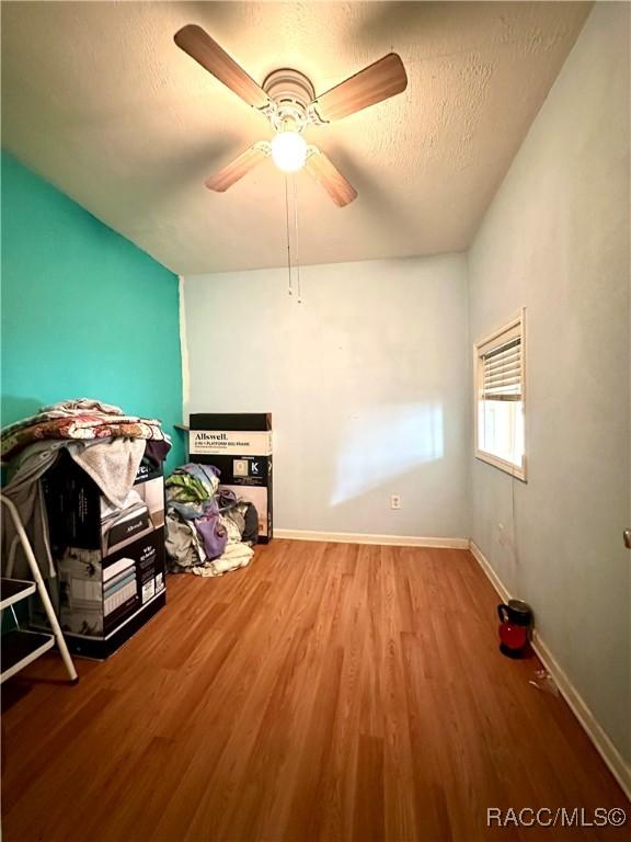 interior space with ceiling fan, wood-type flooring, and a textured ceiling