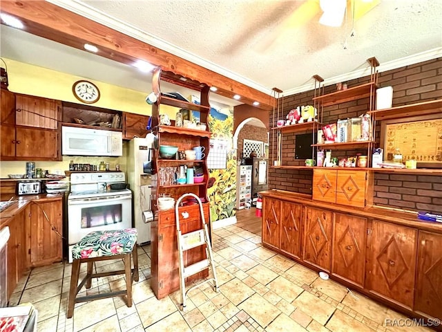 kitchen with brick wall, a textured ceiling, and white appliances