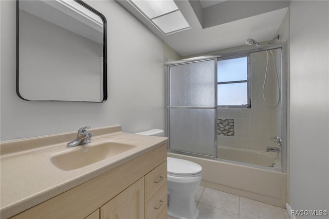 bathroom with tile patterned flooring, toilet, vanity, and combined bath / shower with glass door