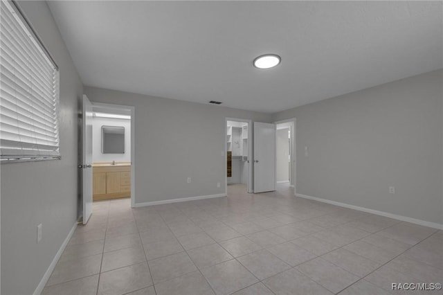 unfurnished bedroom featuring a spacious closet, visible vents, baseboards, and ensuite bathroom